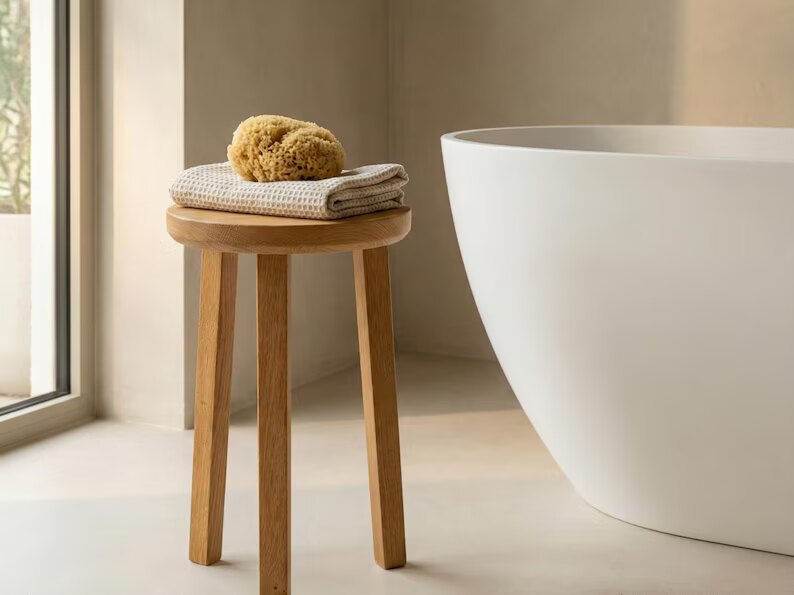 Runder Eichen-Hocker im Badezimmer neben der Badewanne mit Handtüchern
