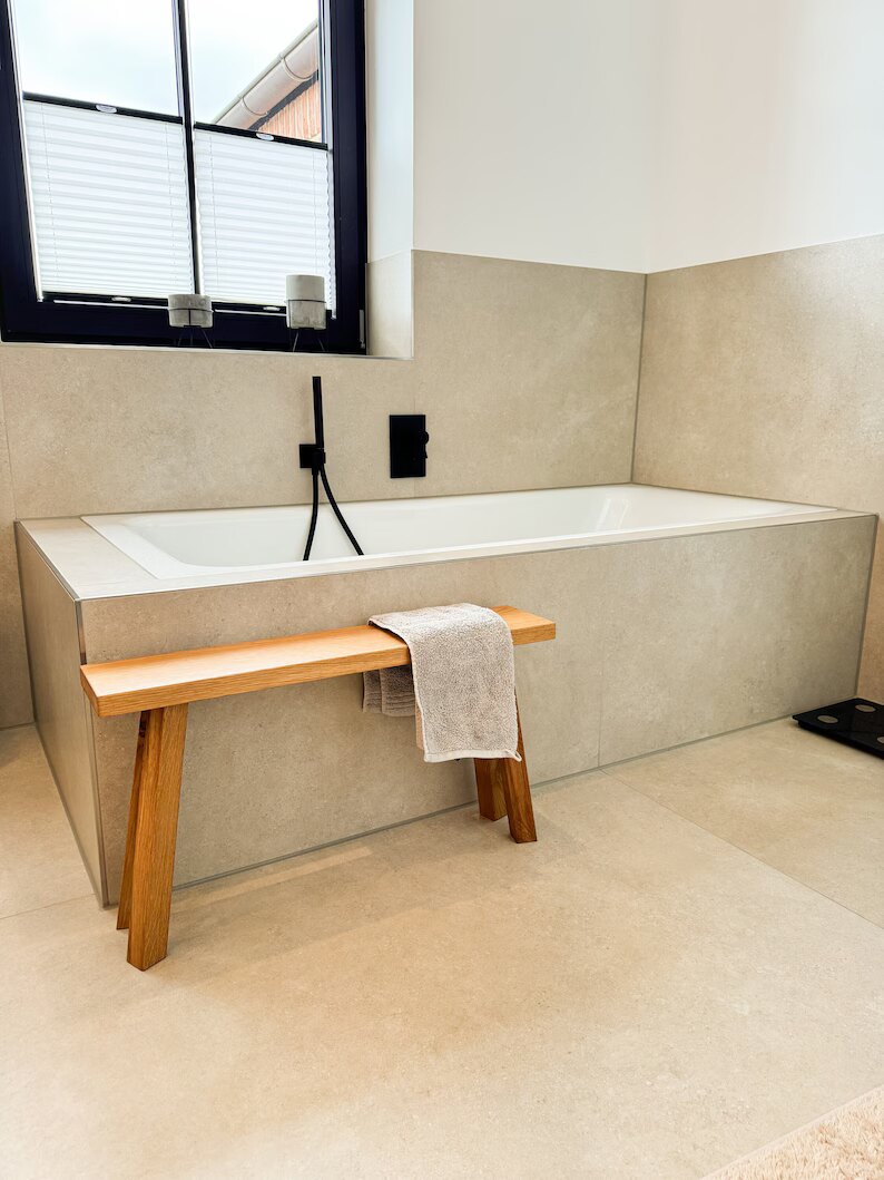 Schmale Eichenbank im Badezimmer neben der Badewanne mit Handtuch